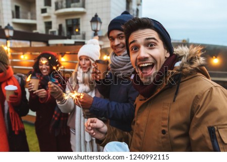 Image of a happy young friends talking with each other drinking coffee outdoors winter concept take a selfie by camera.
