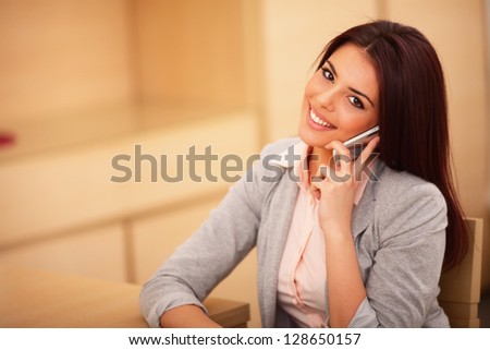 Beautiful business woman talking on cell phone and looking at camera