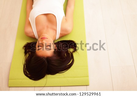 Young woman in sport cloths lying on the yoga mat