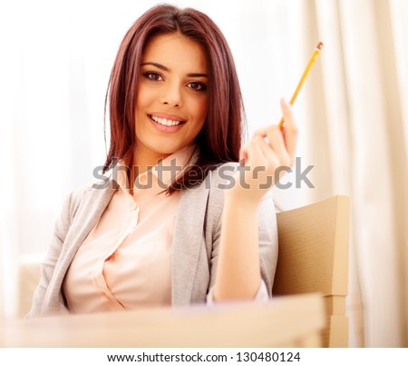 Portrait of a young beautiful confident woman in casual business cloths holding a pencil