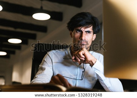 Portrait of a confident concentrated businessman working at the office late at night, working on computer