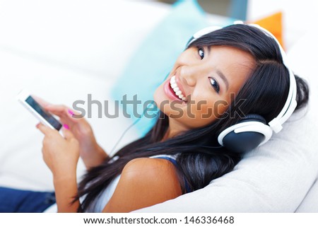 Closeup portrait of a young asian woman in headphones listening to music with her smartphone