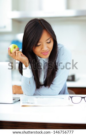 Young happy asian woman reading newspaper and eating apple