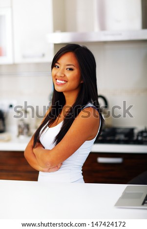 Young happy asian woman with arms folded at home