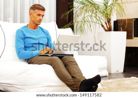 Young man using laptop computer at home, looking at screen
