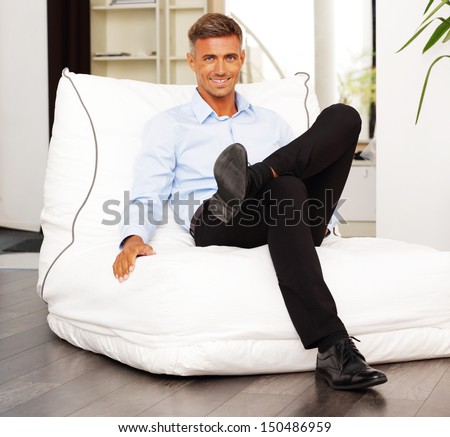 Handsome confident man sitting in armchair at home