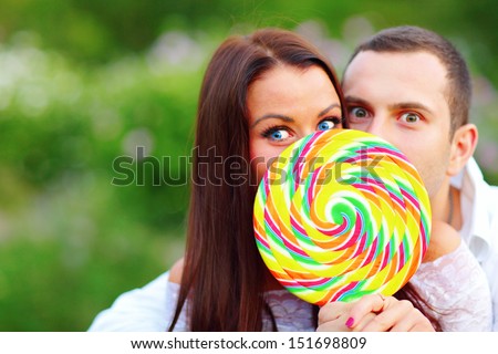 Young surprised couple covering their faces with huge colorful candy