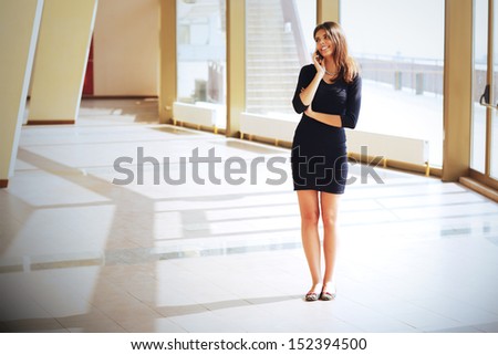 Businesswoman talking on phone standing in office hall