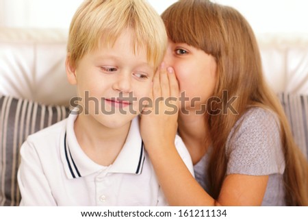 girl whispers something to her brother