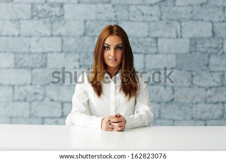 Young serious businesswoman sitting at the table in office