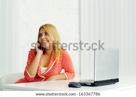 Young relaxed businesswoman talking on phone at office