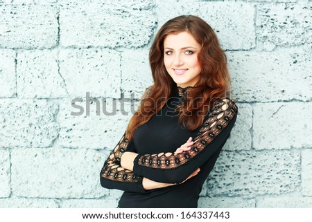 Confident young woman with arms folded against brick wall