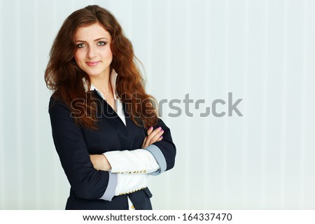 Beautiful young businesswoman standing with arms folded at office