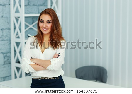 Young beautiful businesswoman standing with arms folded at office