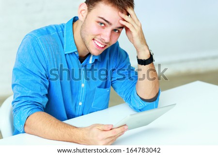 Portrait of a young businessman holding tablet computer and looking at the camera in office
