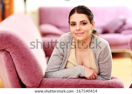 Young beautiful happy woman lying on the couch at home