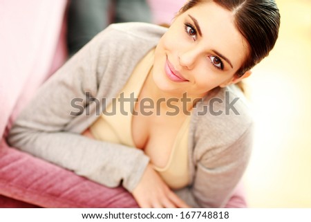 Closeup portrait of a beautiful smiling woman lying on the couch at home
