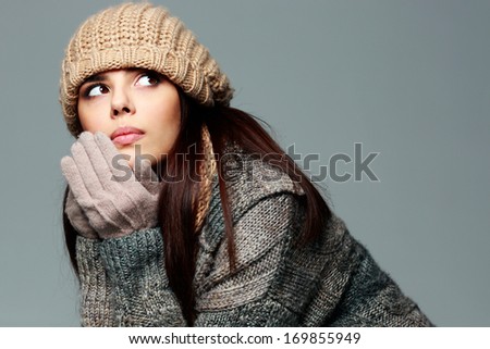 Young pensive woman in warm winter outfit looking away