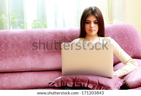 Young beautiful woman sitting on the sofa and using laptop at home