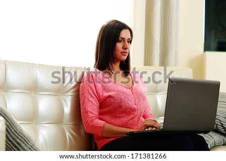Young beautiful woman sitting on the sofa with laptop at home