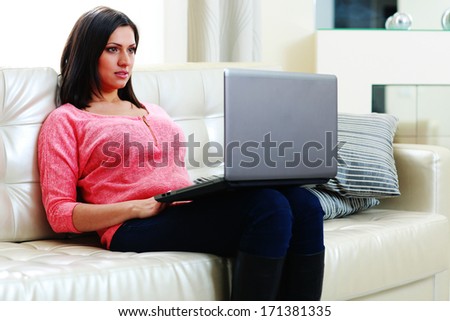 Young beautiful woman sitting on the sofa with laptop at home