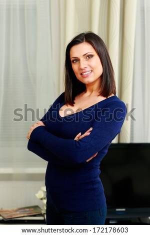 Portrait of a young cheerful woman standing with arms folded