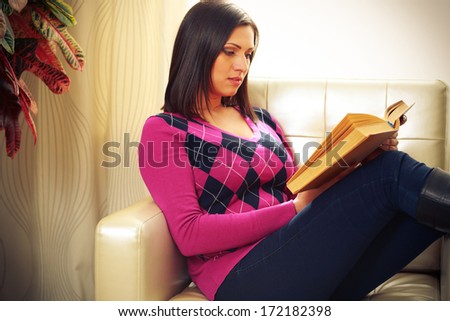 Middle-aged beautiful woman sitting on the sofa and reading the book