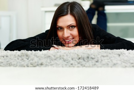 Middle-aged happy smiling woman lying on the carpet at home