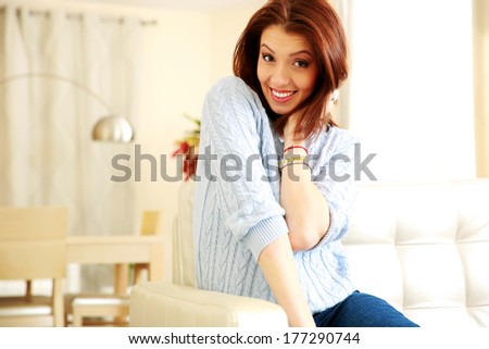 Happy beautiful woman sitting on the sofa at home