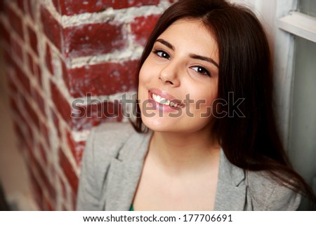 Portrait of a young smiling woman near brick wall