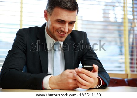 Happy businessman using smartphone at office