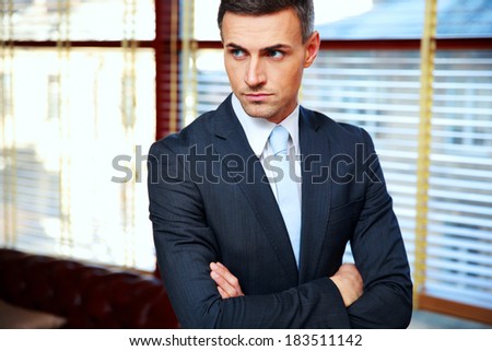 Handsome businessman with arms folded in office