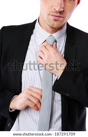 Businessman straightening his tie over white background