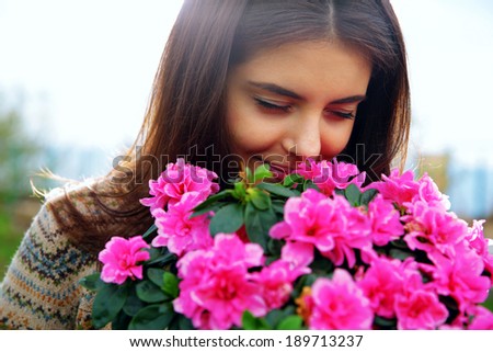 Portrait of a young happy woman smelling pink flowers