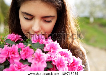 Portrait of a young woman smelling pink flowers
