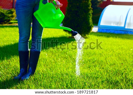 Woman (only legs) watering lawn with water pot