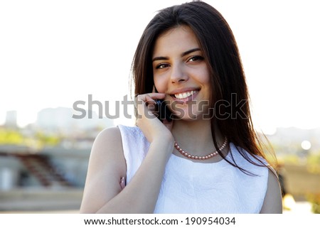 Portrait of a smiling woman speaking on the phone outdoors