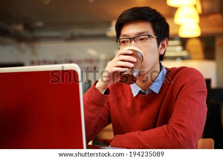 Young asian man working on laptop and drinking coffee
