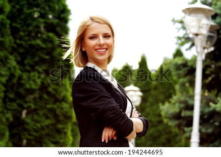 Portrait of a smiling attractive woman with arms folded in park