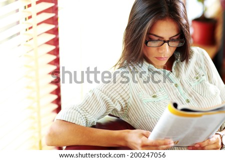 Businesswoman reading magazine in modern office