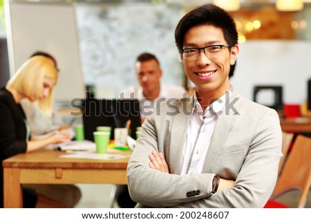 Portrait of cheerful businessman with arms folded sitting in front of colleagues