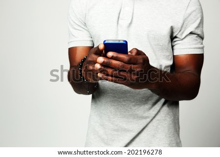 Closeup portrait of a male hands using smartphone on gray background Closeup portrait of a male hands using smartphone on gray background