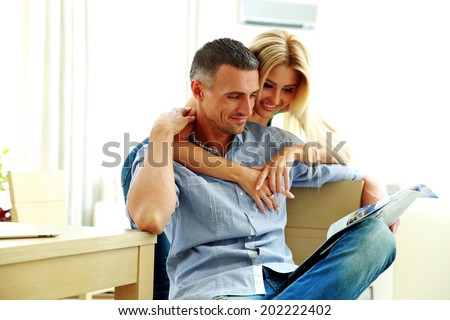 Smiling young couple reading magazine at home
