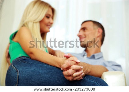 Young couple sitting on the sofa at home. Focus on hands