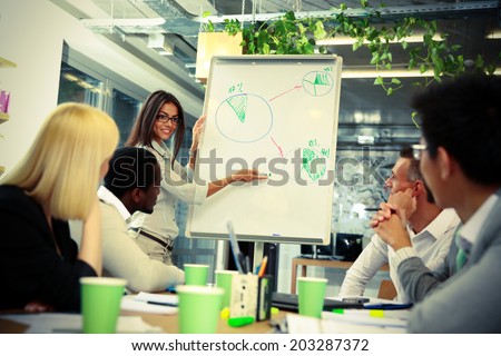happy businesswoman explaining graph to his colleagues