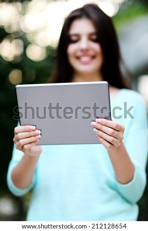 Portrait of a woman holding tablet computer. Focus on tablet computer
