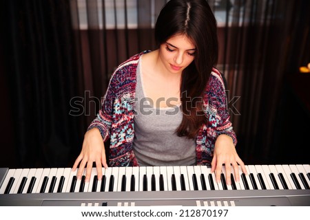 Young beautiful woman playing on piano at home