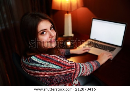 Back view portrait of a beautiful woman using laptop and looking at camera