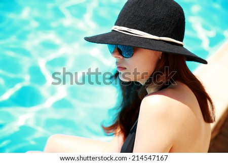 Beautiful woman sitting on the ledge of the pool