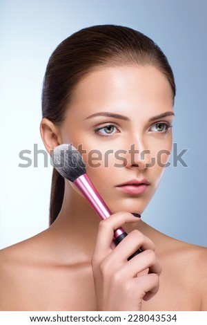 Beautiful woman with fresh skin holding brush for makeup